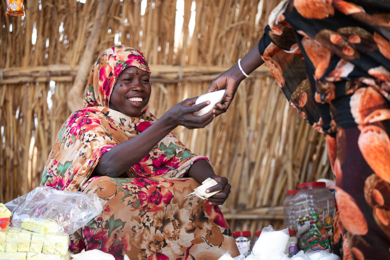 Rayga smiling as she serves a customer at her shop.